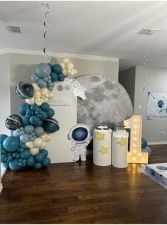 a room with balloons, stars and moon decorations on the wall next to a wooden floor