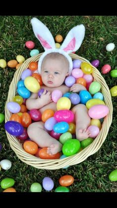 a baby in a basket filled with easter eggs