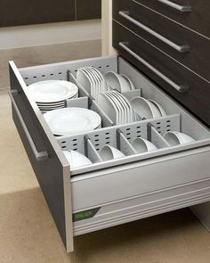 an open drawer with plates and cups in it next to a cabinet full of other dishes