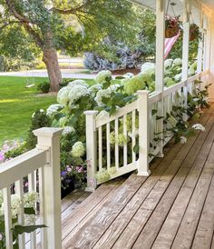 a porch with white railings and flowers on it