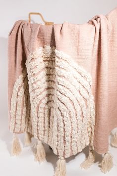 a pink blanket with tassels hanging from it's sides and a white background