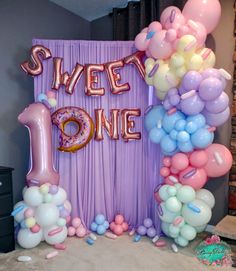 balloons and streamers fill the backdrop for a sweet one birthday party in pink, blue, and white