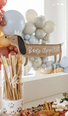 a table topped with balloons and plates filled with cake pops next to a sign that says bone appetit