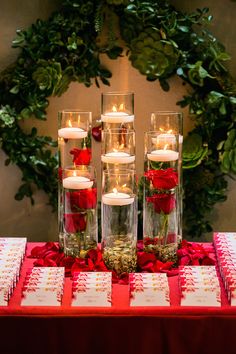 a table topped with lots of vases filled with flowers and candles