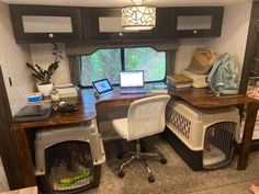 a desk with two dogs in their kennels and a laptop on the desk