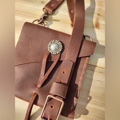 Artisan Made Wells Leather City Bag, Brown Oil Tanned Leather Crossbody With Silver Concho And Leather Lasso Closure Copper Hardware, Back Pocket Holds Cell Phone, Id. Lipstick Etc..Bag Measures 7” H X 7.””W Adjustable Strap. Strap Can Be Adjusted From 52” To 56” Length. Custom Colors And Orders Welcome. Boho Festival Western Moto Motorcycle Hippie Cowgirl Handmade Leather Pouch Belt Bag, Everyday Leather Shoulder Bag With Hand Tooled Details, Leather Tote Belt Bag With Removable Pouch, Everyday Leather Strap Crossbody Shoulder Bag, Everyday Leather Strap Crossbody Bag, Leather Shoulder Bag With Removable Pouch For Personal Use, Artisan Leather Saddle Bag With Leather Handles, Hand Tooled Leather Bag For Everyday, Artisan Leather Crossbody Bag