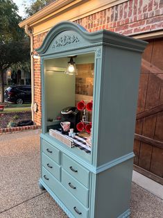 an old dresser has been painted blue and is sitting in front of a brick building