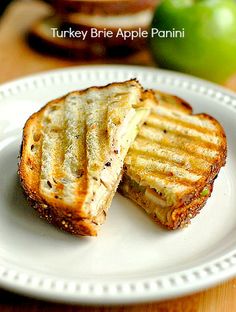 two grilled sandwiches on a white plate with an apple in the background