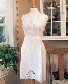 a white dress on a mannequin in front of a window with a potted plant