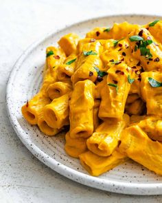 a white plate topped with pasta covered in cheese