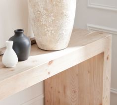 two vases sitting on top of a wooden shelf next to each other in front of a white wall