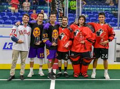 a group of young men standing next to each other on top of a hockey field