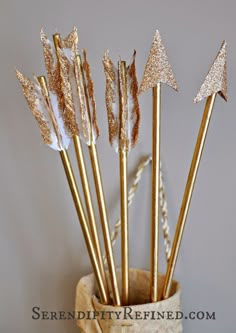 five gold and white glittered arrows in a burlock bag with twine