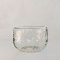 a clear glass bowl sitting on top of a white tableclothed surface with no one around it