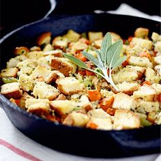 a skillet filled with stuffing and vegetables on top of a red and white checkered table cloth