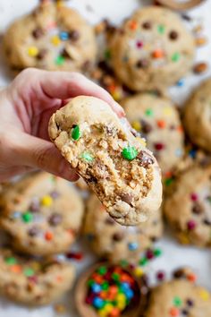 a hand holding a cookie with m & m cookies in the background