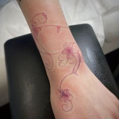 a woman's arm with a flower tattoo on the left side of her wrist