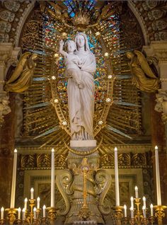 the statue is surrounded by candles in front of an ornate alter with stained glass windows