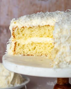 a slice of coconut cake on a plate with the rest of the cake in the background