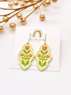 Hand-Painted Flower Cameo Earrings Add a touch of nature-inspired elegance to your outfit with these hand-painted floral cameo earrings. Crafted with intricate floral details and hand-painted peach and green flowers, these medium-sized dangle earrings are made from pale yellow polymer clay, making them lightweight and comfortable to wear all day long.  Available in both gold and silver-colored hardware (select your choice at checkout) *Made from lightweight polymer clay. *Hand painted with acrylic paint. *Hypoallergenic stainless steel or gold plated stainless steel ear wires. *2" L x 7/8" W **PROCESS** Each piece is designed, cut, sanded and assembled by me in the USA. Because of their handmade nature, each earring is unique and slight variations may occur from one another - that is what Tulip Earrings, How To Clean Earrings, Clay Making, Clay Hand, Cameo Earrings, Earrings Clay, Brown Jewelry, Polymer Crafts, Peach And Green