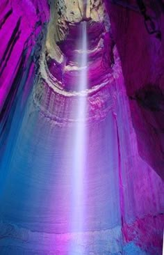 the light shines brightly in this cave like structure, which is surrounded by purple and blue rock formations