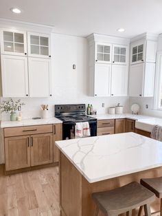 a large kitchen with white cabinets and marble counter tops on the island in front of two stools