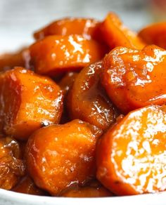 close up view of cooked carrots with sauce on them in a white bowl, ready to be eaten