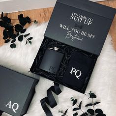 two personalized flasks in a black gift box on a white fur rug