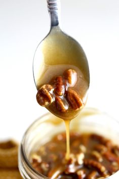 a spoon full of caramel sauce being drizzled with nuts