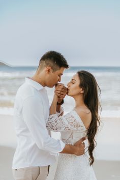 a man and woman standing next to each other on a beach