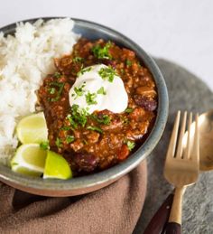 a bowl filled with chili and rice next to a fork