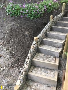 stone steps leading up to the top of a hill with purple flowers in the background