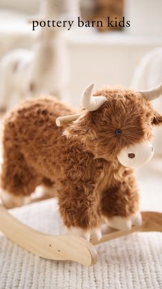 a stuffed cow is sitting on a wooden rocking toy with the caption pottery barn kids