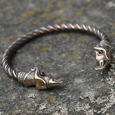 two silver bracelets with red stones on them sitting on top of a stone surface