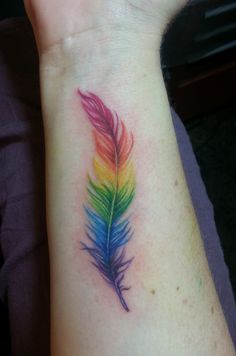 a small colorful feather tattoo on the left wrist and right arm, with an instagram message below it