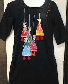 a black t - shirt with three people hanging from it's sides and colorful pom poms around the neck