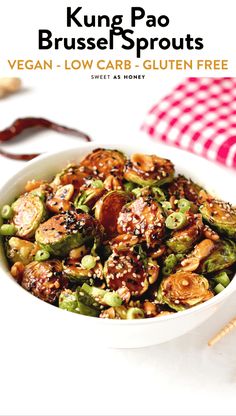 a white bowl filled with vegetables and nuts on top of a table next to chopsticks