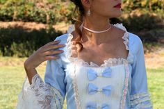 a woman wearing a blue and white dress standing in the grass with her hands on her hips