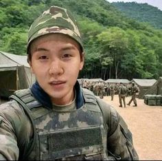 a young boy in camouflage is taking a selfie with his army uniform and helmet