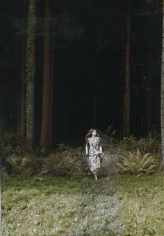 a woman is running through the grass in front of some trees