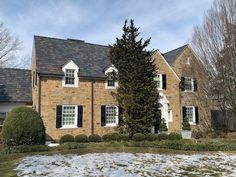 a brick house with black shutters and snow on the ground