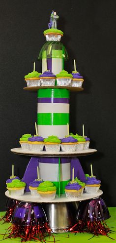 a three tiered cake with cupcakes on the top and green icing