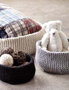 three crocheted baskets with stuffed animals in them and one is sitting on the floor