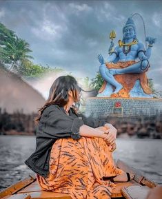 a woman sitting on top of a boat next to a statue