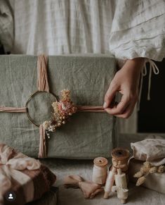 a person is holding a wrapped present with flowers and twine on it, surrounded by other items