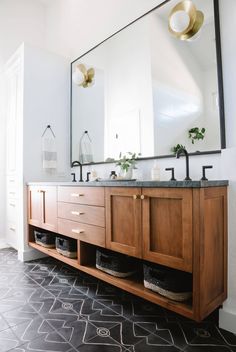 a bathroom with two sinks and a large mirror on the wall above it is tiled flooring