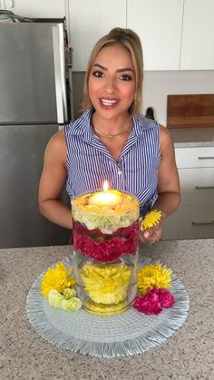 a woman standing in front of a cake with a lit candle on top of it