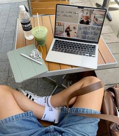 a woman is sitting at a table with her legs crossed and laptop on her lap