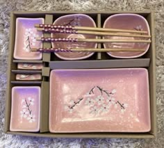 an assortment of pink dishes and chopsticks in a box on carpeted floor