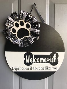 a welcome sign with a dog's paw hanging on the front door to someones house